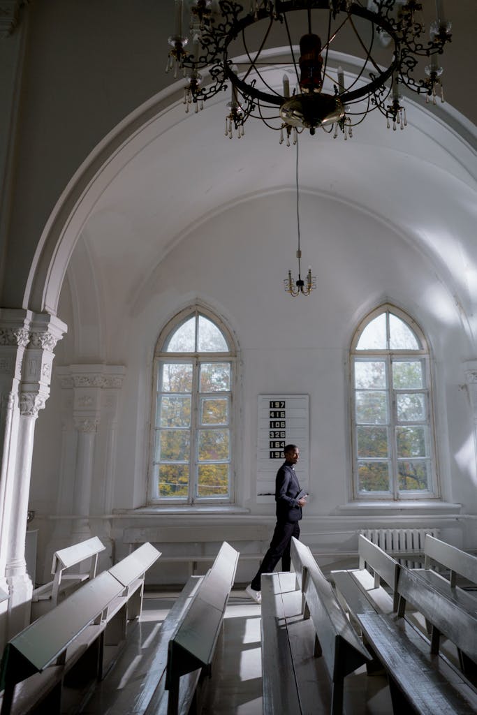 A serene interior of a church with a person in thoughtful prayer, illuminated by soft natural light.