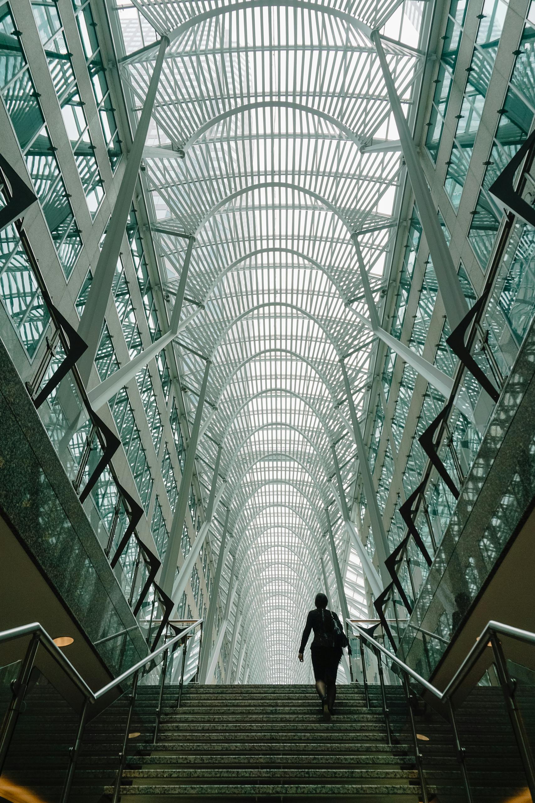 Stunning vertical shot of a modern atrium with a person ascending the staircase in Toronto's iconic Brookfield Place.